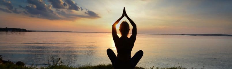 silhouette of woman practicing yoga in front of sunset