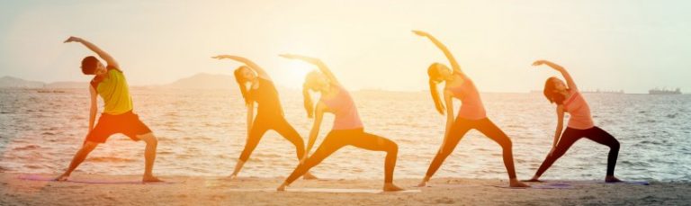 People doing yoga on the beach