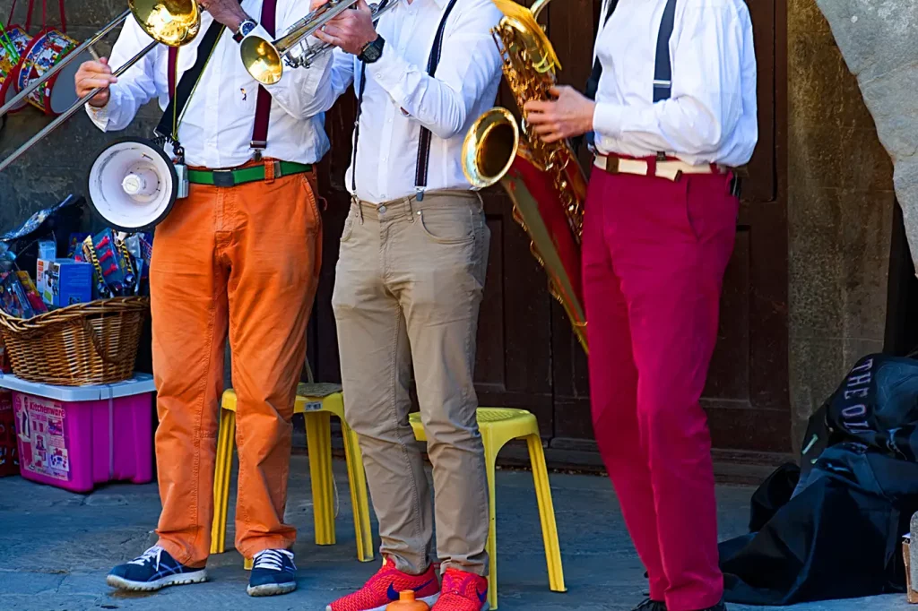 Three band members wearing colorful pants playing brass instruments