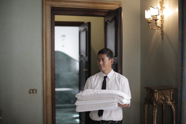 a man in a dress shirt and tie holding a stack of towels
