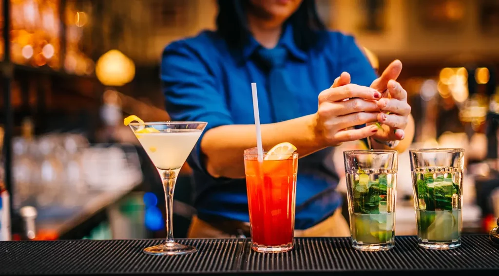 Bartender preparing a line of cocktails.