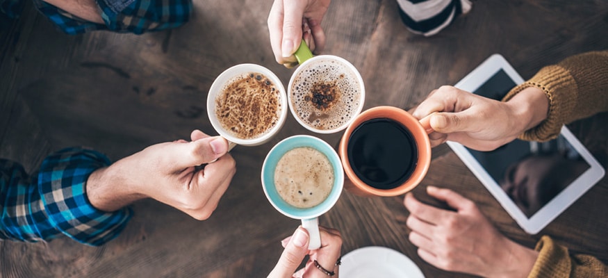 People holding out coffee mugs