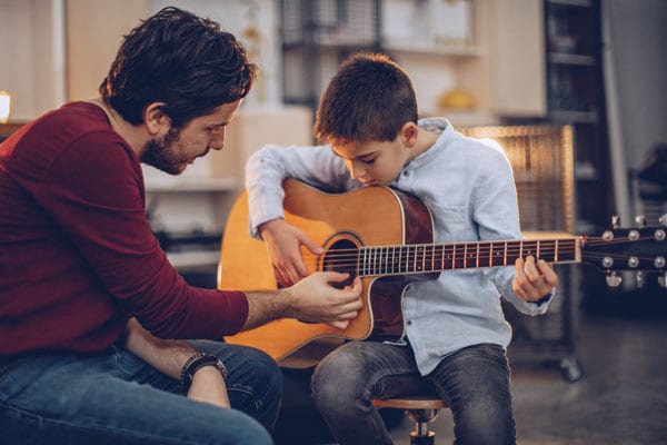 Man teaching boy to play the guitar