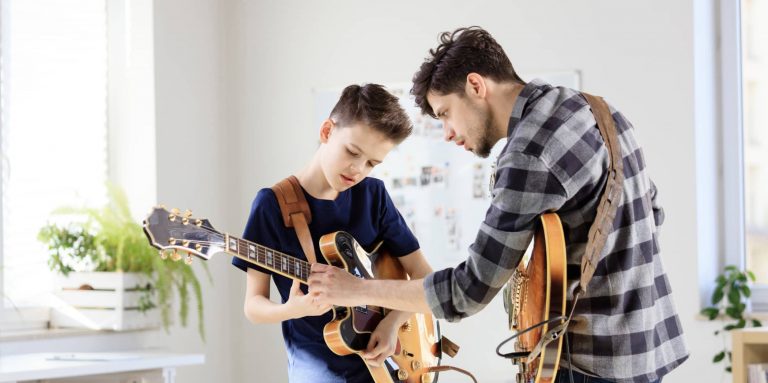 music teacher helping student with guitar chords