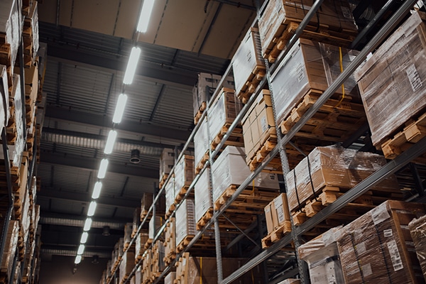 A worker stands among products in a warehouse.