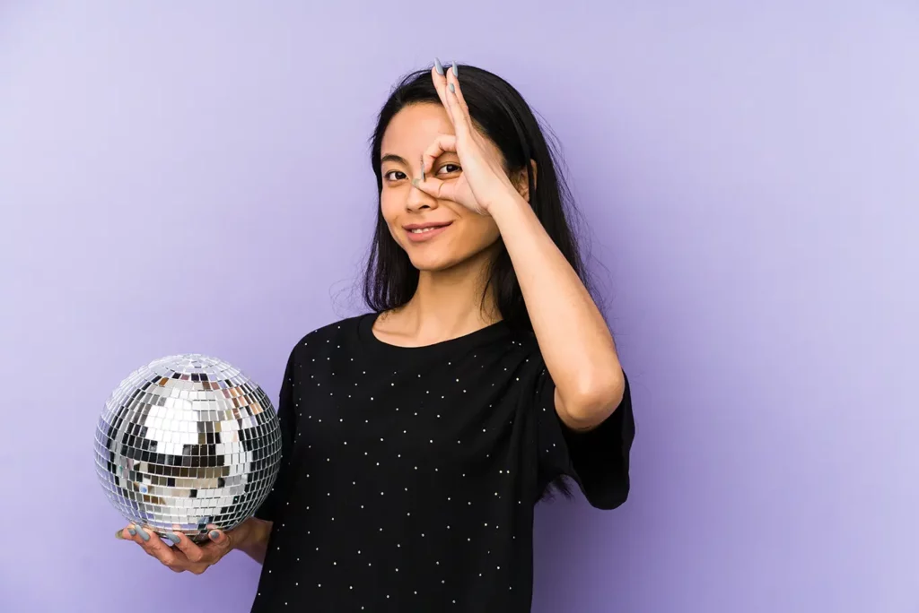 Person on a purple background holding a disco ball in their hand.