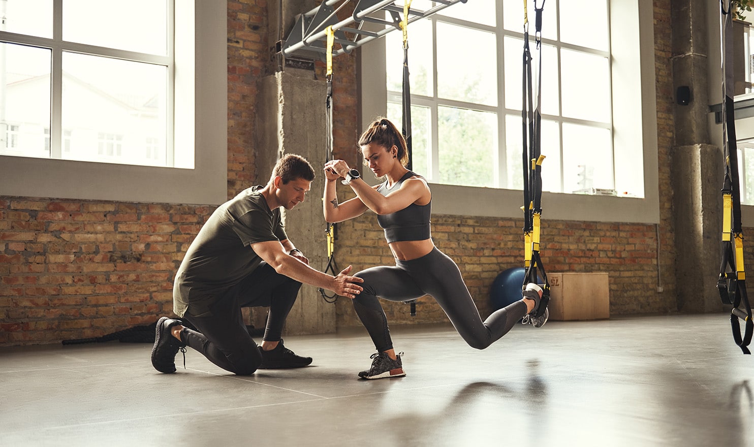 An athletic trainer works with a client using straps to help her improve her core balance and strengthen muscles to prevent injuries.