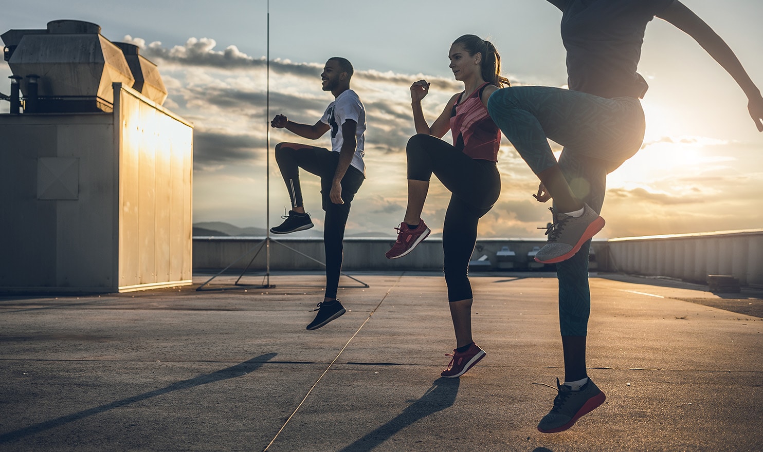 A personal trainer works with two athletes outdoors to help them increase strength and build stamina.