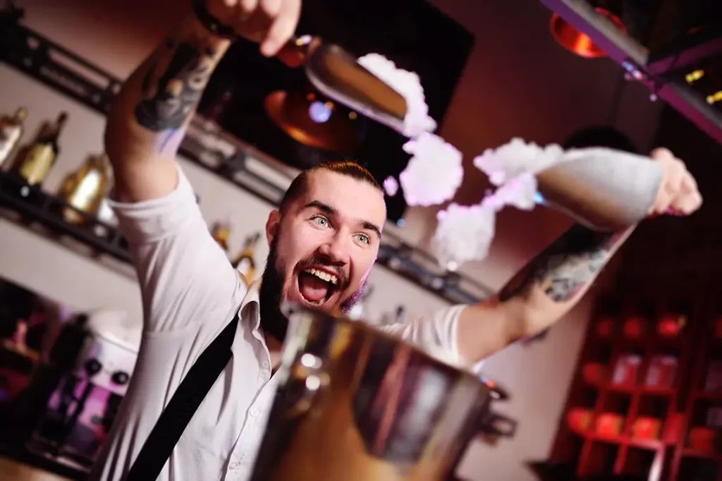 A bartender adding ice to cocktails.