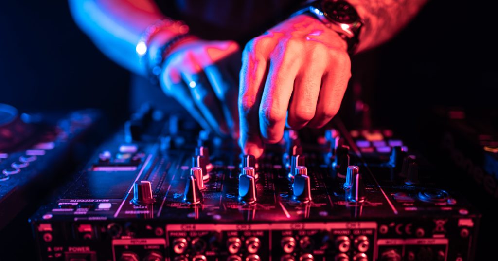 close up of DJ hands controlling a music table in a club