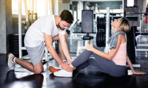 A fitness instructor is assisting a client who injured her ankle during a workout.