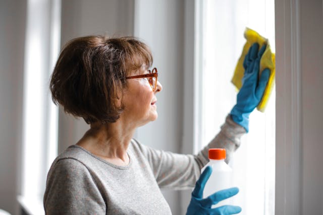 a woman wearing rubber gloves cleaning a window