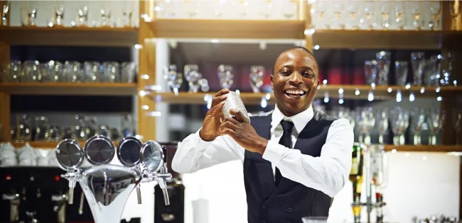 A smiling bartender shaking up a cocktail.