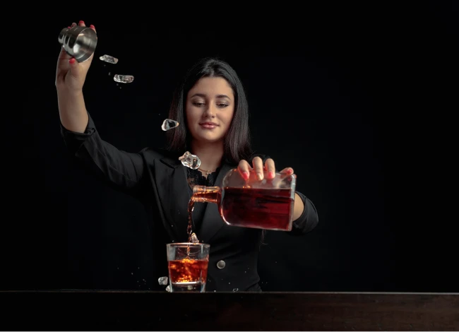 A private event bartender pouring brandy and ice.