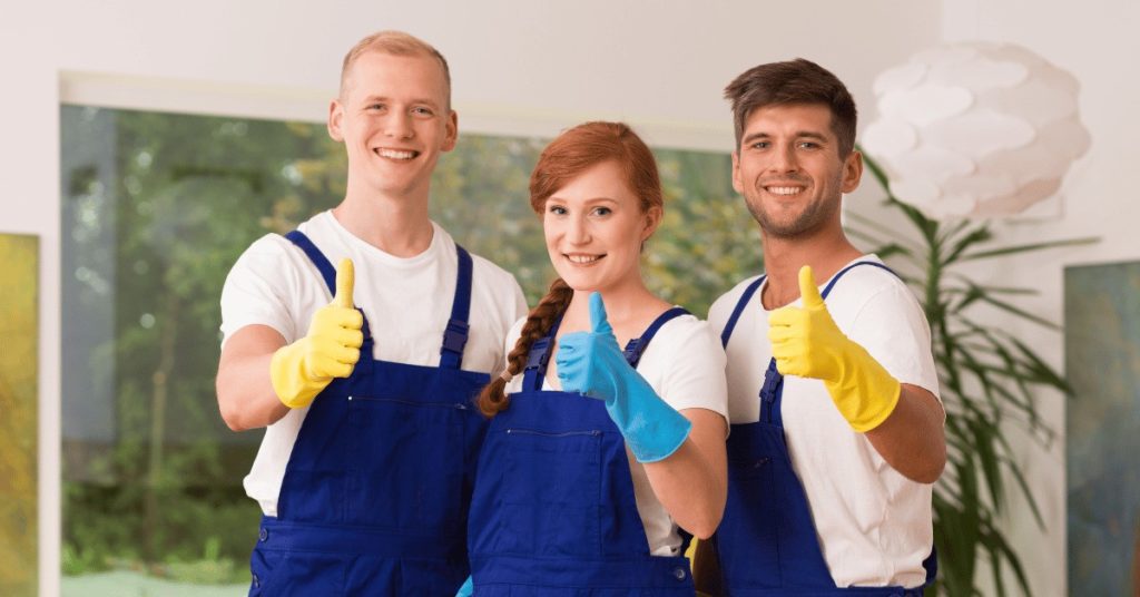 a cleaning crew trio each holds up a thumbs up sign