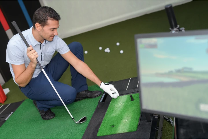 Golfer using monitoring technology places a golf ball on an indoor green.