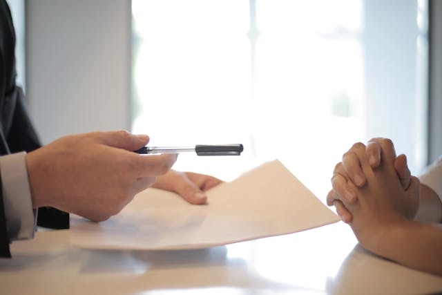 a document and pen extended to a client