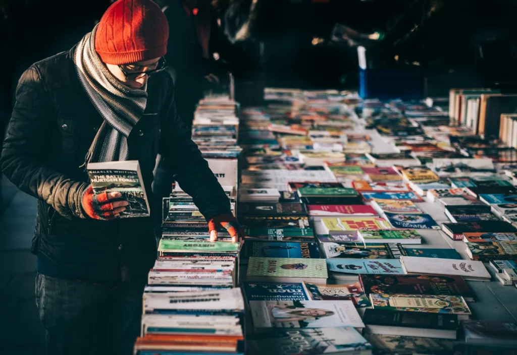 An outdoor vendor sells books to customers at a cold event.