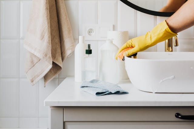 a gloved hand cleaning a sink
