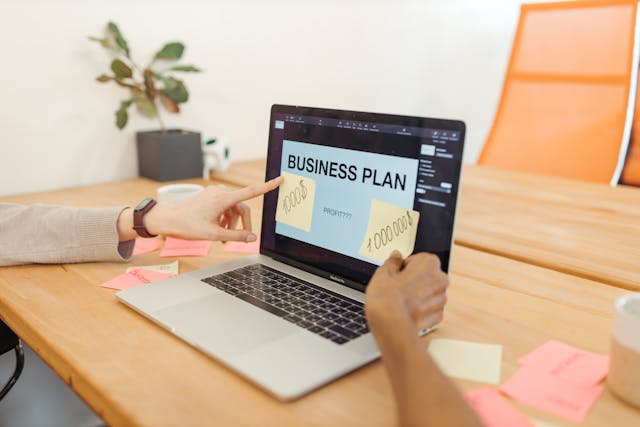 a computer sitting on the desk with the words "business plan" on the screen