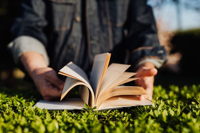 hands flipping through a book on top of a hedge