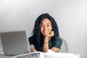 a woman sitting in front of a laptop smiles with confidence