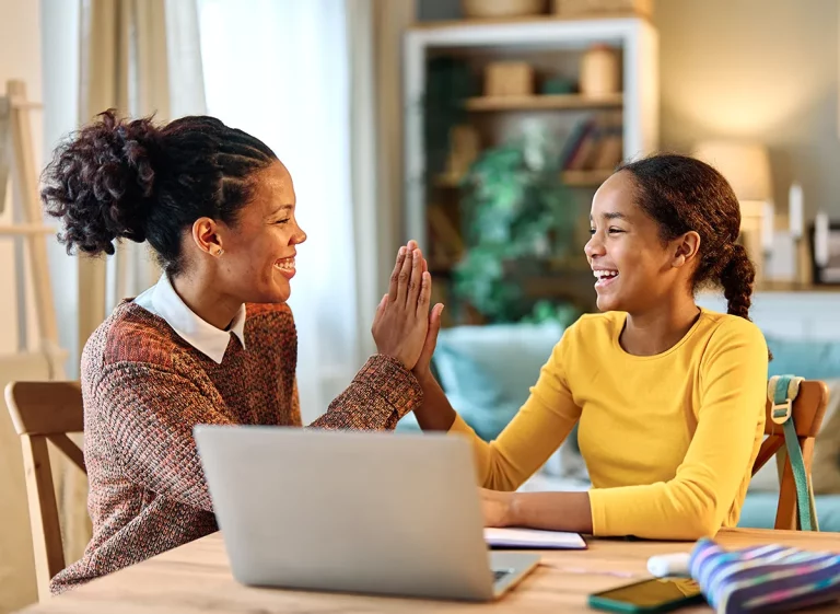 A tutor high-fives her female student during a tutoring session.