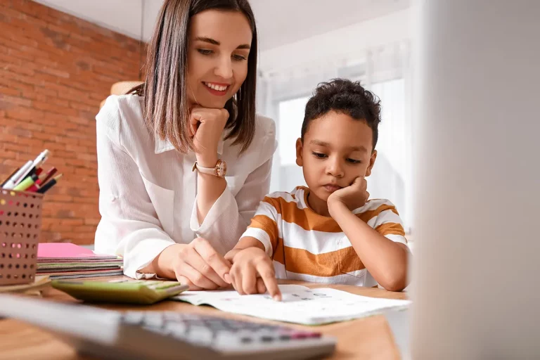 A young boy receives instructions from a tutor at home.