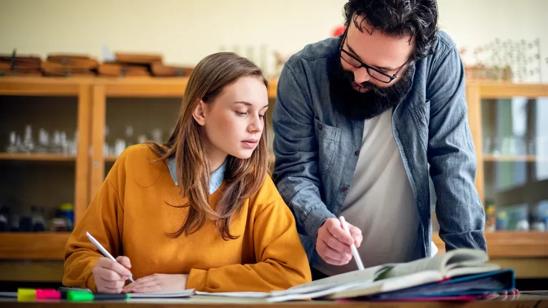 A male tutor helps a student with chemistry homework.