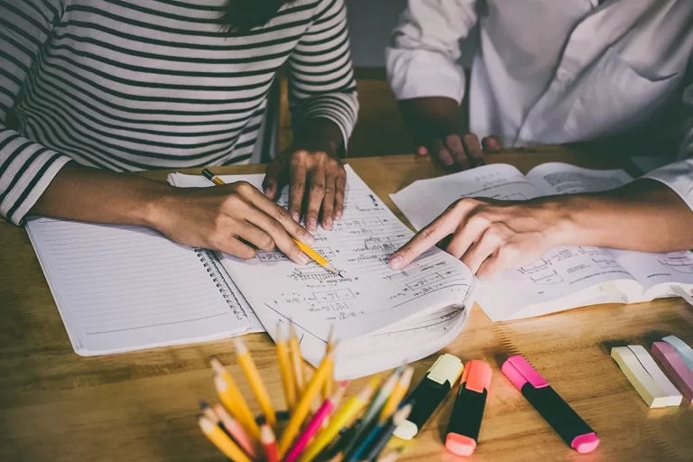 A close-up of a tutor helping a student with their math homework.