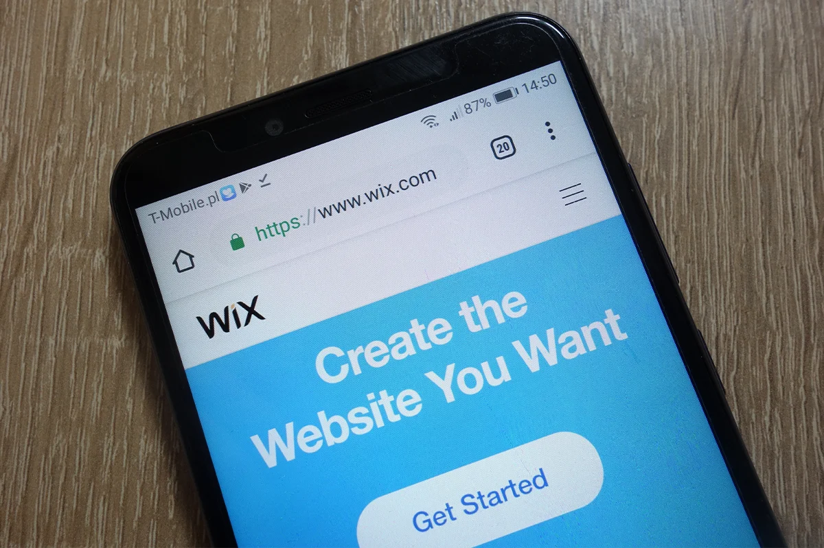 Wix.com homepage displayed on a smartphone laying on a brown wooden table.