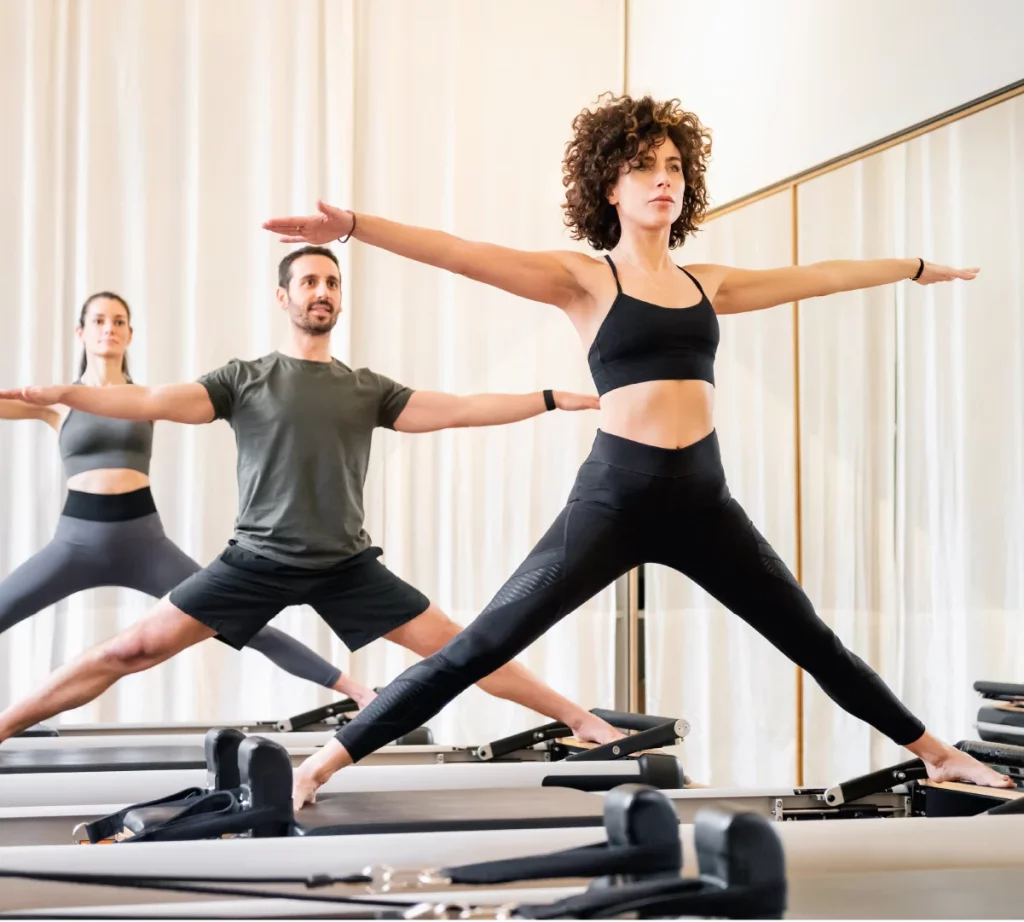 Yoga class utilizing the Reformer machine to do side split exercises.