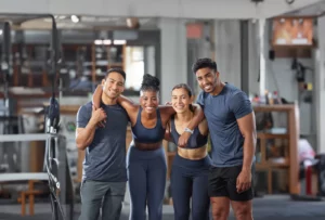 Two male and two female CrossFit athletes wearing blue workout clothes smile and pose at the gym.