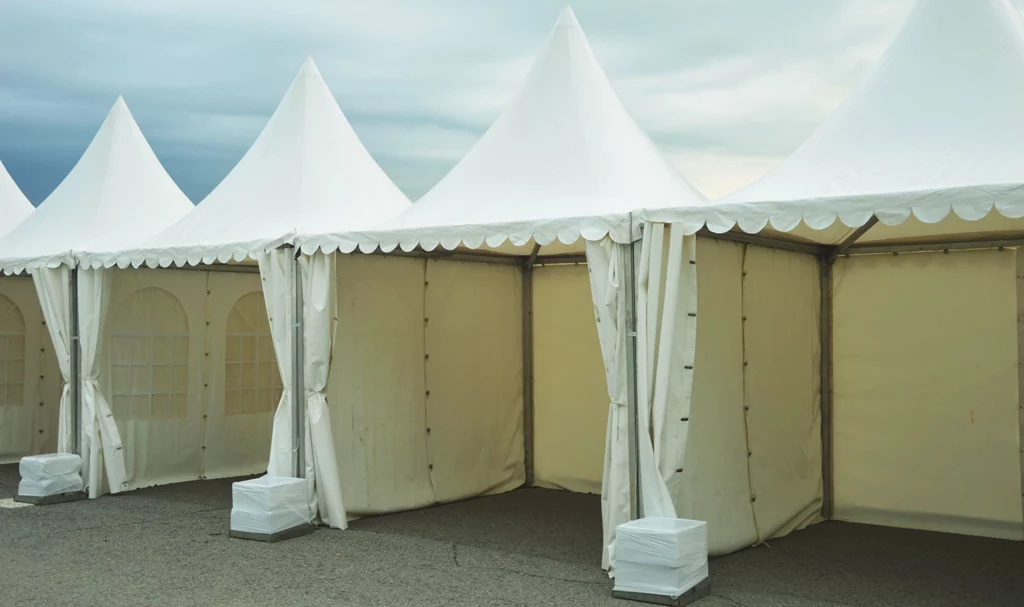 A row of empty vendor booth tents outside with weights to keep them steady.