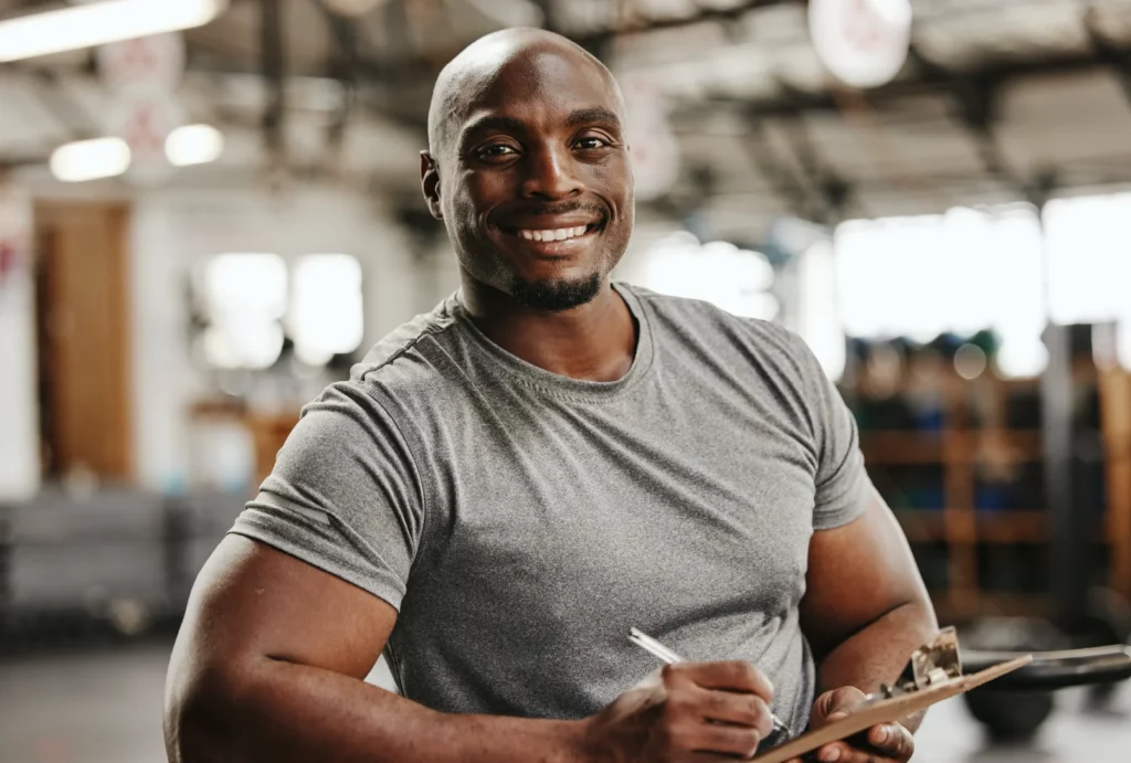 A strong man writing on a clipboard in a gym