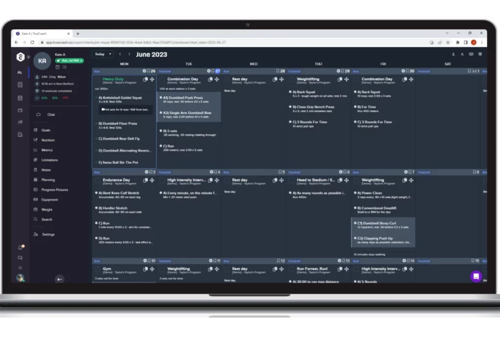 A sleek silver laptop displays the TrueCoach workout generator feature for a user named "Kate A" for June 2023. The calendar is listed from Monday to Saturday with detailed workouts for each day, titles including, "heavy duty," "combination day," "rest day," and "weightlifting." The screen is a deep gray-blue with pops of blue, green, and white text. A sidebar on the left shows stats and other features, such as chat, goals, nutrition, and more.